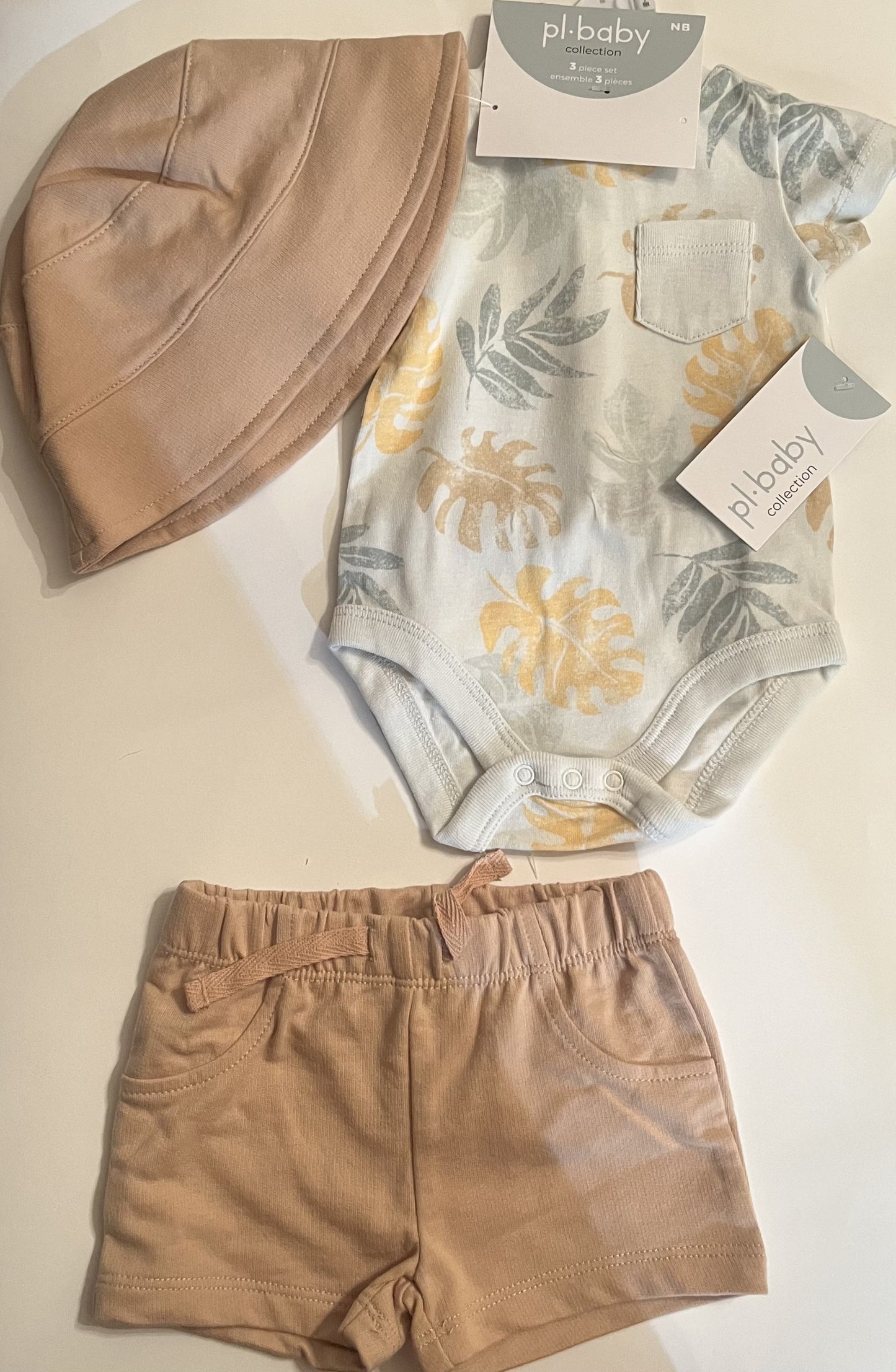 Ensemble 3 pièces beige, cache-couche imprimé de feuilles, short et chapeau unis.