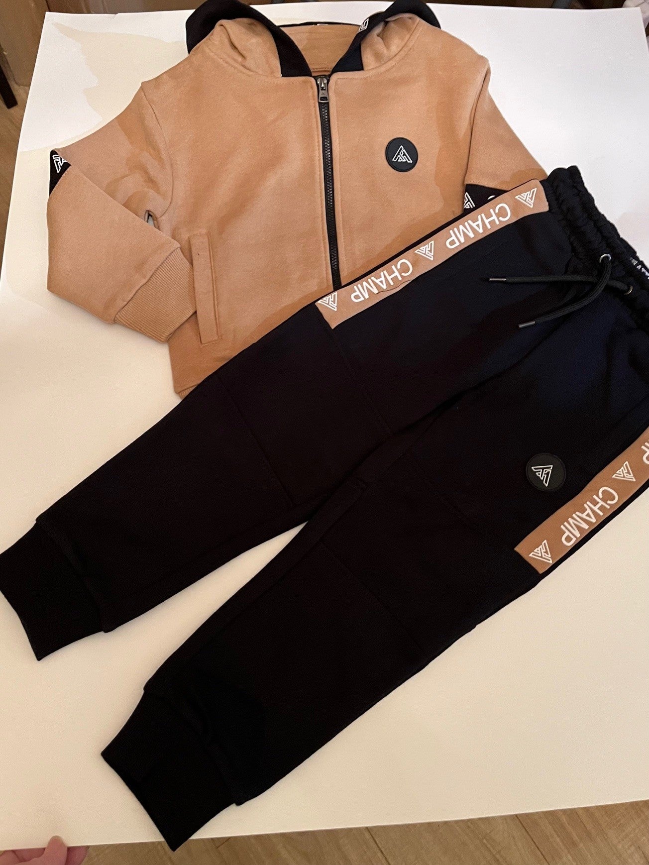 Ensemble jogging sport-veste beige a capuche zippé et jogging noir.